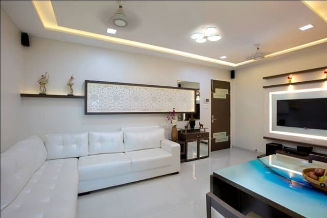 The Compact Living Room with White & Brown Combination has L Shaped White Upholstered Sofa with Wooden Side Table cum Storage Unit The Compact Living Room with White & Brown Combination has L Shaped White Upholstered Sofa with Wooden Side Table cum Storage Unit