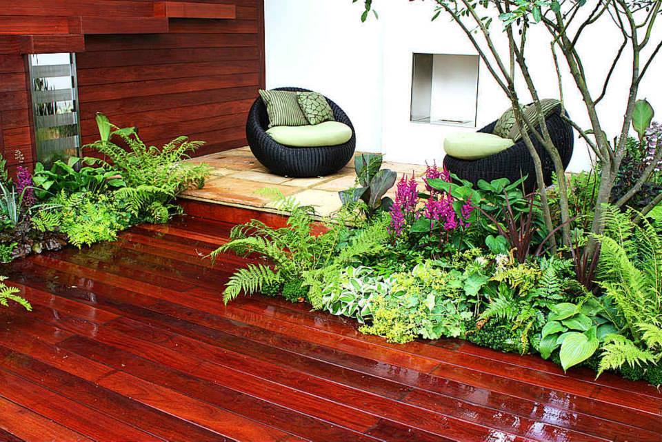 Wooden Outdoor Patio with Outdoor Round Wicker Chairs & Plants surrounded