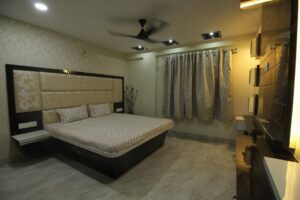 Bedroom designed with Wooden Bed, Side Tables attached with High Cushioned Headboard
