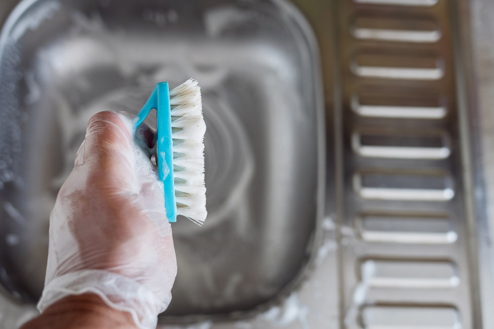 Scrubbing The Rust Stain With The Paste Of Baking Soda And A Brush
