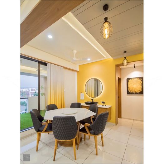 A minimalist dining area with a yellow wall and round mirror with side lights