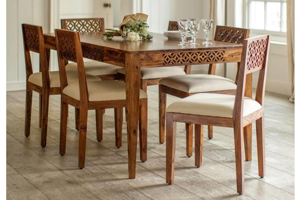 The 6 Seater Wooden Dining Table has Wooden Legs with Beautiful Carving on the Table Border & Backrest of the Chair