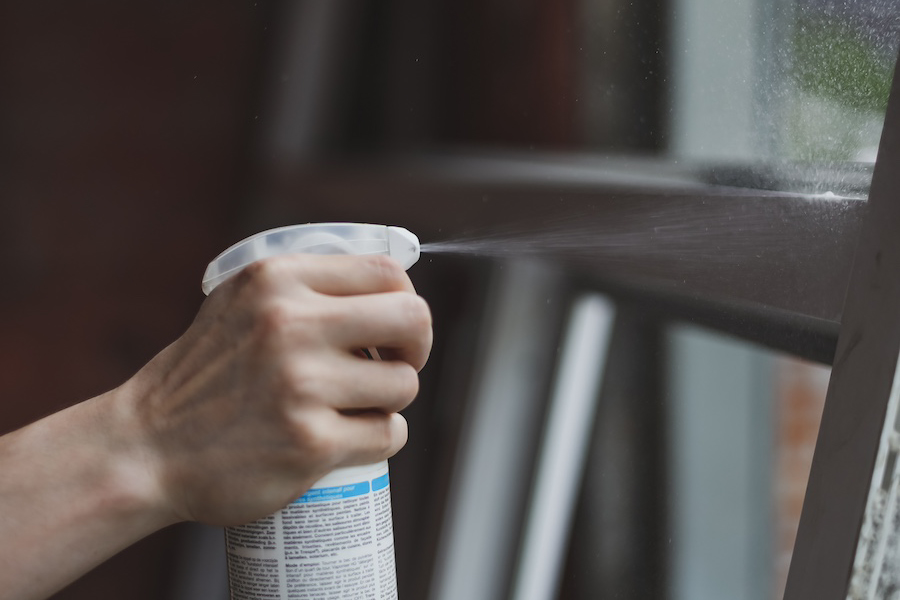 Applying Paint Remover Spray on Vinyl Window Frame