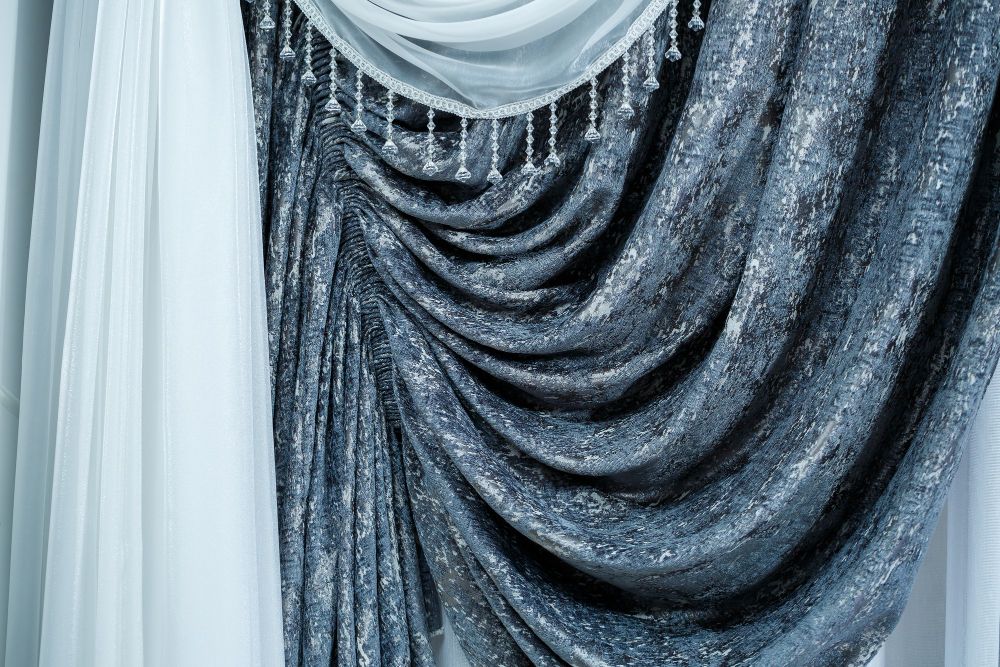 Elegant window curtains and sheer tulle layering in an apartment interior, with fabric texture visible.