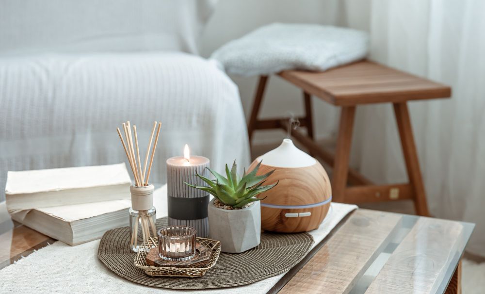 Interior table arrangement with incense sticks, candles, books, and diffuser creating a calming atmosphere.